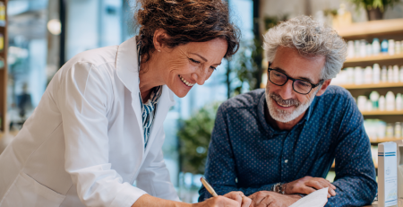 Farmacist explicând cum se citește corect prospectul unui medicament într-o farmacie modernă.